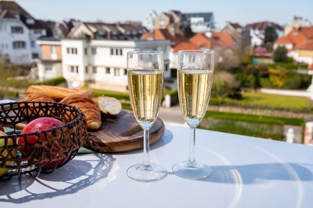 Drinking of brut champagne sparkling wine in flute glasses on outdoor cafe or bistro terrace in France on sunny dayの写真素材
