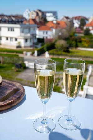 Drinking of brut champagne sparkling wine in flute glasses on outdoor cafe or bistro terrace in France on sunny dayの写真素材