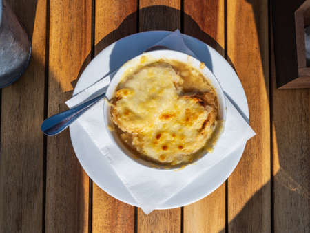 French caramelized onion soup with croutons and gruyere cheese from oven close up