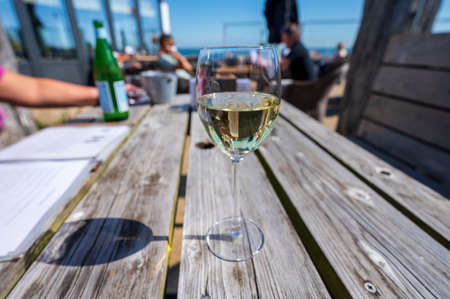 Glasses of white wine served on outdoor terrase with seaview in sunny day, summer vacationの写真素材