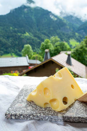Cheese collection, French cow cheese emmental and french mountains village in Haute-Savoie in summer on backgroundの写真素材