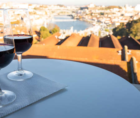 Tasting of different fortified dessert ruby, tawny port wines in glasses with view on Douro river, porto lodges of Vila Nova de Gaia and city of Porto, Portugal, on sunsetの写真素材