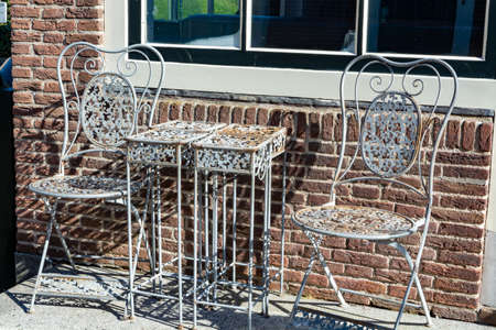 Vintage metal bistro table and chairs set in outdoor cafe, used for breakfast, lunch and dinner on terraceの写真素材