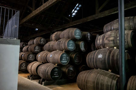 Old porto lodge with rows of oak wooden casks for slow aging of fortified ruby or tawny porto wine...