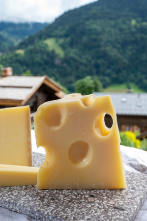 Cheese collection, French cow cheese emmental and french mountains village in Haute-Savoie in summer on backgroundの写真素材