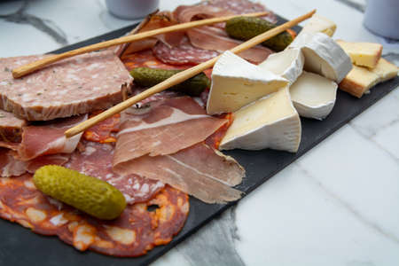 Meat and cheese assortment served on black stone board
