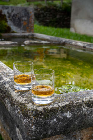 Glasses of strong scotch single malt whiskey served on old stone reservoir for water from mountain spring, Scotlandの写真素材
