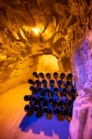 Bottles on racks in deep and long undergrounds caves, making champagne sparkling wine from chardonnay and pinor noir grapes in Reims, Champagne, Franceの写真素材