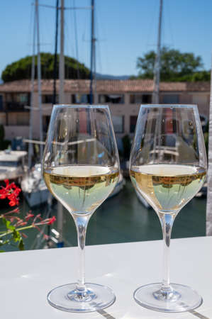Summer on French Riviera Cote d'Azur, drinking cold dry white wine from Cotes de Provence on sunny outdoor terrase in Port Grimaud, Var, France with boats and yachts on backgroundの写真素材