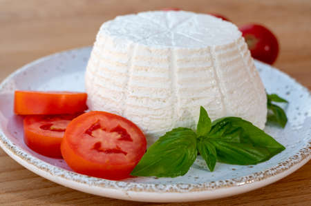 Cheese collection, white Italian soft organic cheese ricotta served with fresh tomatoes and basilの写真素材