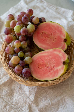 Fresh ripe aromatic pink guava tropical fruit and sweet table grapes ready to eatの写真素材