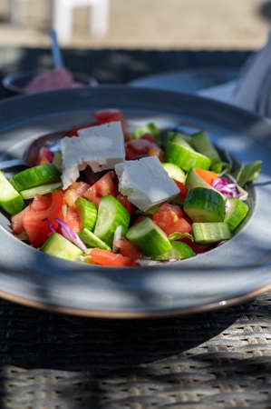 Summer healthy food served outdoor in sunlights, vegetable greek salad made with fresh cucumber, tomatoes, onion, white feta cheeseの写真素材