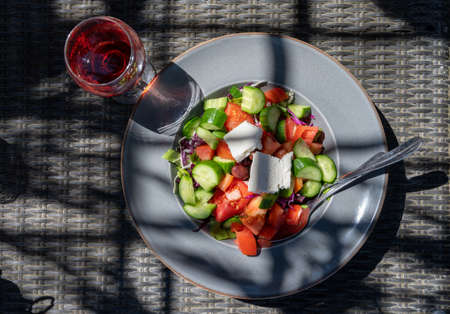 Summer healthy food served outdoor in sunlights, vegetable greek salad made with fresh cucumber, tomatoes, onion, white feta cheeseの写真素材