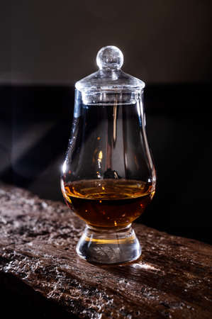 Dram of single malt scotch whisky served in tasting glass on wooden beam