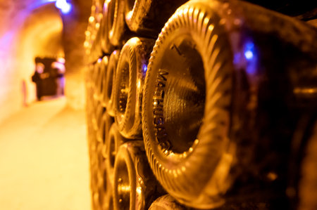 Mathusalem champagne bottles on racks in deep and long undergrounds caves, making champagne sparkling wine from chardonnay and pinor noir grapes in Reims, Champagne, Franceの写真素材