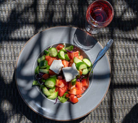 Summer healthy food served outdoor in sunlights, vegetable greek salad made with fresh cucumber, tomatoes, onion, white feta cheeseの写真素材