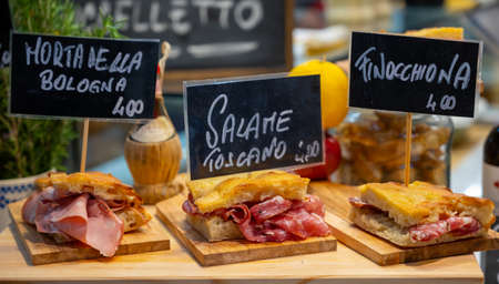 Italian street food, Parma ham sandwiches, bread with cured meats in market in Florence, Italy English translation is: Mortadella from Bologna, Salami from Tuscany and Finocchiona sandwich breadの写真素材