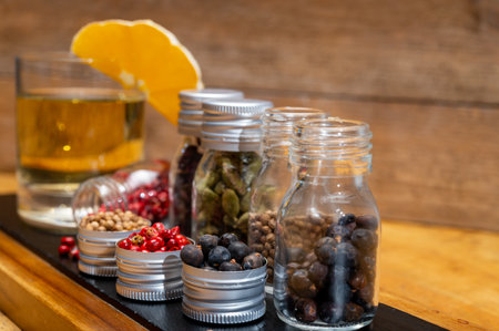 Professional set of gin spices in small bottles, pink pepper, hibiscus flowers, juniper berries, cardamom and coriander seeds close upの写真素材