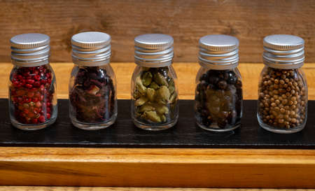 Professional set of gin spices in small bottles, pink pepper, hibiscus flowers, juniper berries, cardamom and coriander seeds close upの写真素材