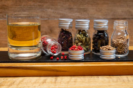 Professional set of gin spices in small bottles, pink pepper, hibiscus flowers, juniper berries, cardamom and coriander seeds close upの写真素材