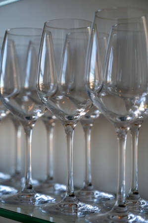 Many empty clean wine and dessert wine glasses on shelf in restaurant