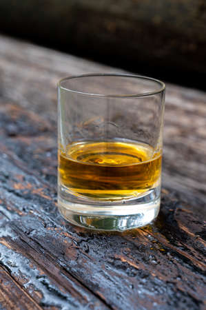 Glass of strong scotch single malt whiskey on old log soaked in creosote, Scotlandの写真素材