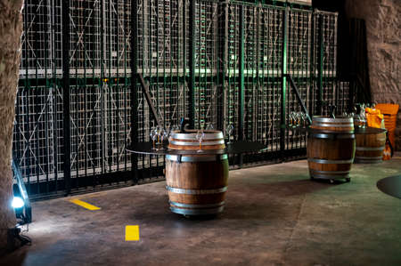 Walking in deep and long undergrounds caves with dusty bottles on racks, making champagne sparkling wine from chardonnay and pinor noir grapes in Reims, Champagne, Franceの写真素材