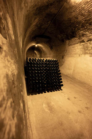 Bottles on racks in deep and long undergrounds caves, making champagne sparkling wine from chardonnay and pinor noir grapes in Reims, Champagne, Franceの写真素材
