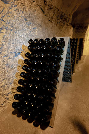Bottles on racks in deep and long undergrounds caves, making champagne sparkling wine from...