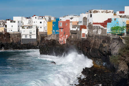 View on colorful houses and black lava rocks in small fisherman village Punta Brava near Puerto de...
