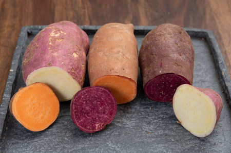Colorful root vegetables pink, purple and orange organic sweet potatos close upの写真素材