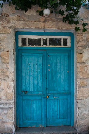 Old blue wooden door in small cypriot village and grapes plantの写真素材