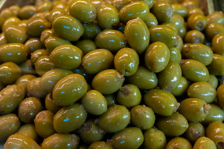 Tasty green olives close up on market, healthy vegetarian food background
