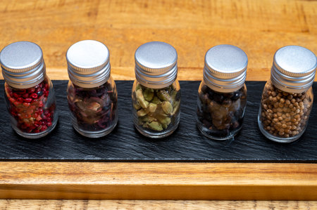 Professional set of gin spices in small bottles, pink pepper, hibiscus flowers, juniper berries, cardamom and coriander seeds close upの写真素材