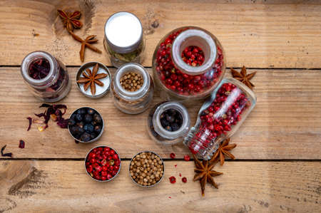 Professional set of gin spices in small bottles, pink pepper, hibiscus flowers, juniper berries, cardamom, coriander seeds, star anise close upの写真素材