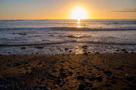 Group of surfers trains in cold water of Atlantic ocean on sunset in winter, Playa de las Americas,...
