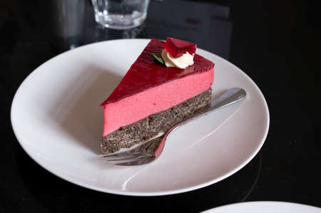 Piece of famous Poppy seed cake with raspberry mousse of Austrian origin served with whipped cream...