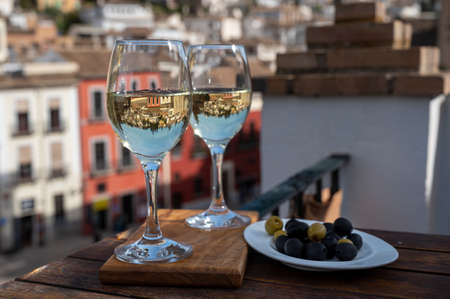 Two glasses of Spanish dry rueda verdejo white wine served on roof terrace with view on old part of Andalusian town Granada, Spainの写真素材