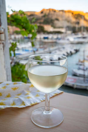 Cold white wine from Cassis winemaking region served in glass on outdoor terrace with view on old...