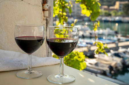 Drinking of red dry wine on outdoor terrace with view on old fisherman's harbor with colorful boats in Cassis, Provence, Franceの写真素材