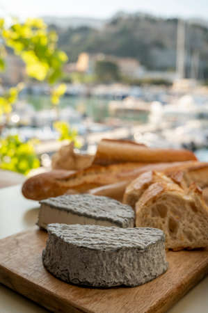 French goat cheese selles-sur-cher and fresh croissants served with view on boats in harbor of Cassis, Provence, France, cheese tasting, close upの写真素材