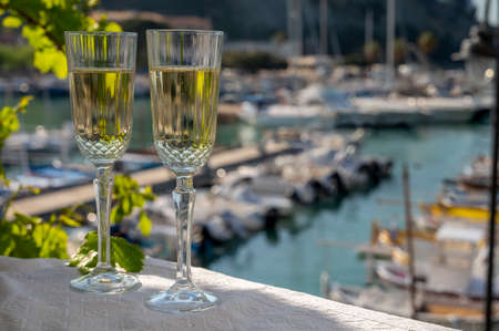 Lunch with two glasses of French champagne sparkling wine and view on colorful fisherman's boats in...