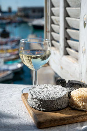 French goat cheeses crottin and selles-sur-cher served with view on boats in harbor of Cassis,...