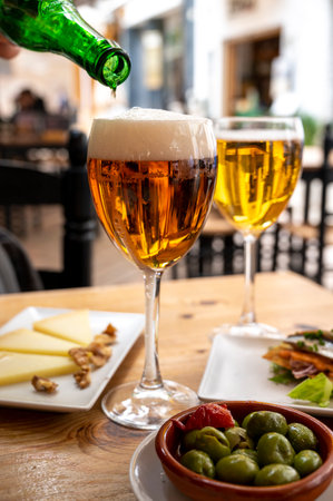 Lunch with cold beer in Spanish outdoor cafe, tapas bowl with green olives and Spanish cheese manchego with nuts, Malaga, Andalusiaの写真素材
