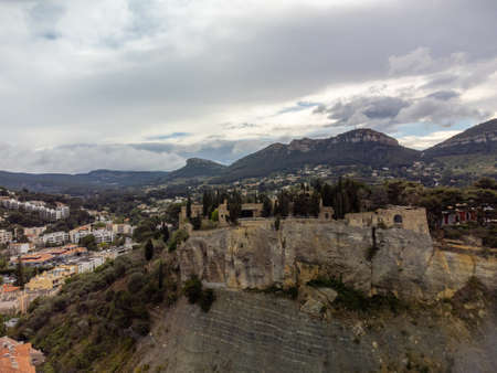Panoramic aerial view on beach, sea, cliffs, houses, streets and old fisherman's harbor with lighthouse in Cassis, Provence, France in cloudy dayの写真素材