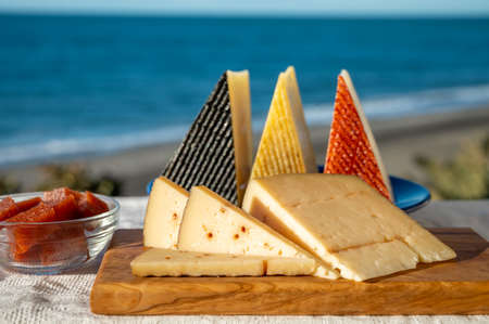 Assortment of Spanish hard cheeses, curado, manchego, goat cheese served outdoor with membrillo jam...