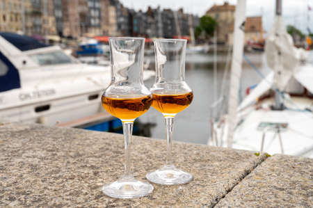 Tasting of apple calvados drink from glasses in old Honfleur harbor with boats and old houses on background, Normandy, Franceの写真素材