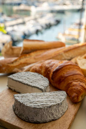 French goat cheese selles-sur-cher and fresh croissants served with view on boats in harbor of Cassis, Provence, France, cheese tasting, close upの写真素材