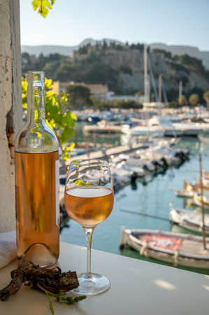 Cold rose Provencal wine in glass and bottle served in sunlights on outdoor terrace with view on old...