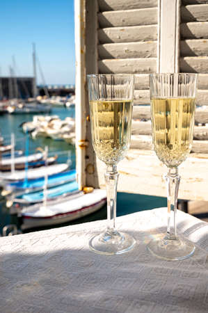 Lunch with two glasses of French champagne sparkling wine and view on colorful fisherman's boats in old harbor in Cassis, Provence, Franceの写真素材